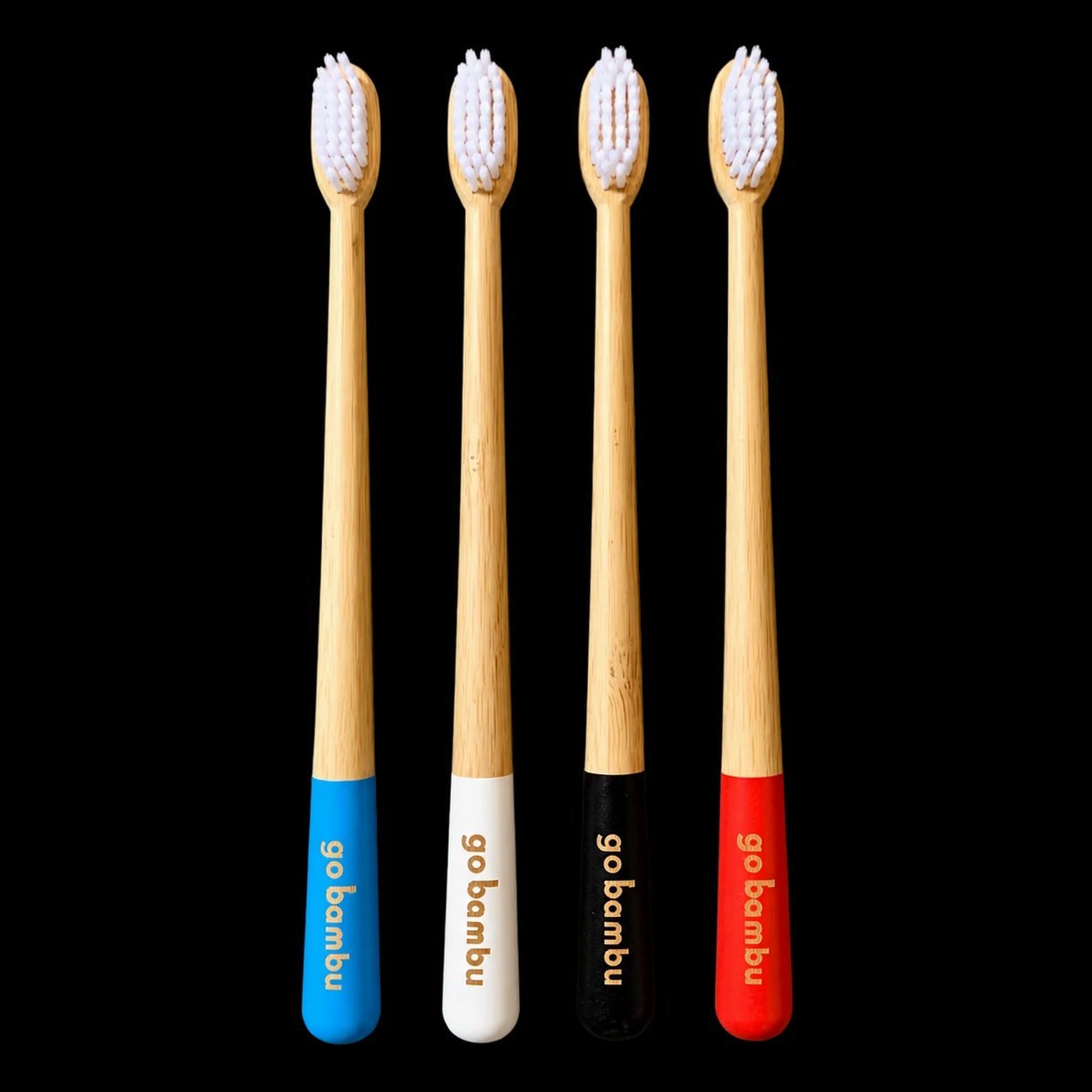 Four goBambu bamboo toothbrushes with blue, white, black and red handles
